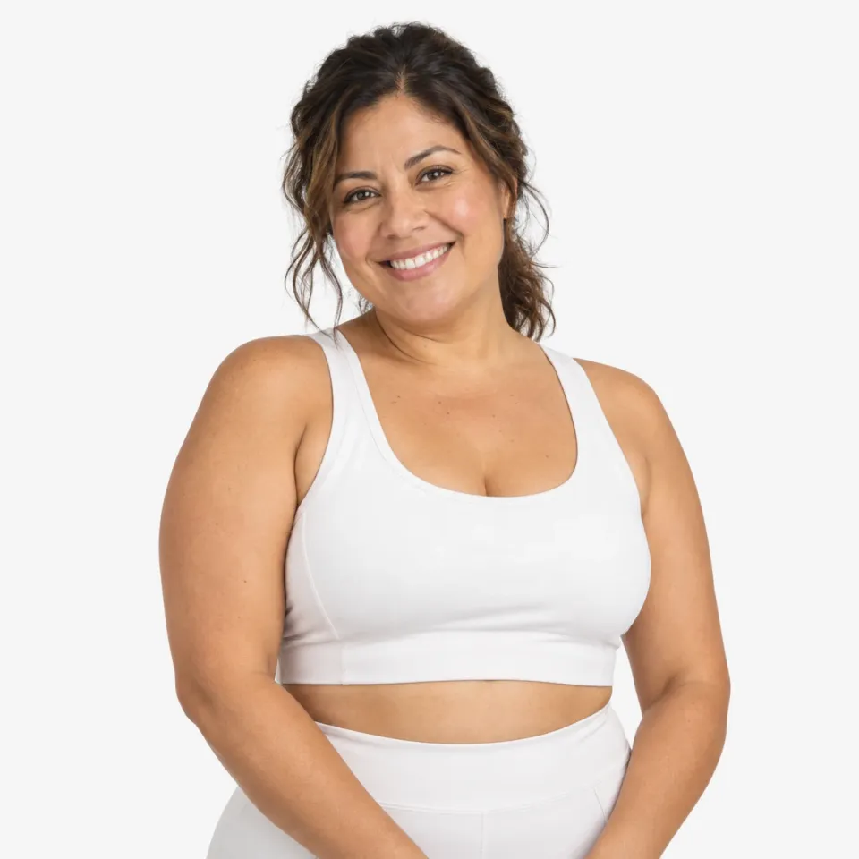 A smiling woman in a white top, against a pale grey background